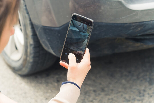 Insurance concept. Outdoor close-up shot of a caucasian woman taking a picture of a front fender after a minor collision. . High quality photo