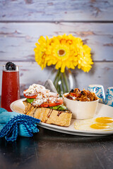 Thick Cut Avocado Toast topped with sliced tomato and a side of granola and 2 fried eggs
