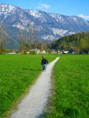 Fototapeta na wymiar Little boy walking alone along pathway in the field. Path in life.