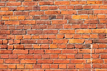 Red brick masonry wall, uneven, broken and black burnt bricks, bright red brick background