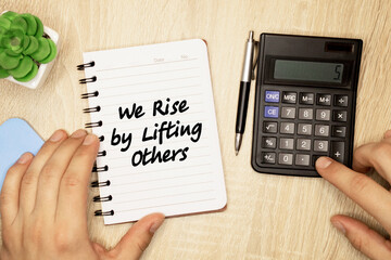 Motivation concept.Text WE RISE BY LIFTING OTHERS writing on notebook.