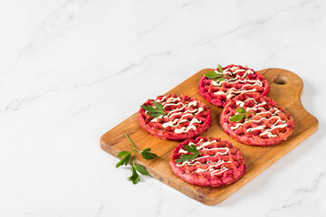 Round beetroot waffles, on a wooden board. Light background. Copy space