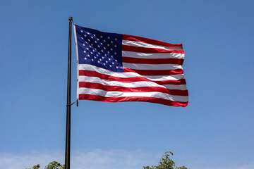 US flag on a blue sky blowing in the wind