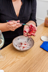 Latin american female chef hands peeling and carving pomegranate. Sweet asian fruit. Raw vegan vegetarian healthy food.