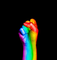 Fist hand symbol with rainbow flag painted raised on black background. Colorful flag sign of same-sex rights, equality of love. LGBTQ pride concept. Social issue awareness. FIght for discrimination.
