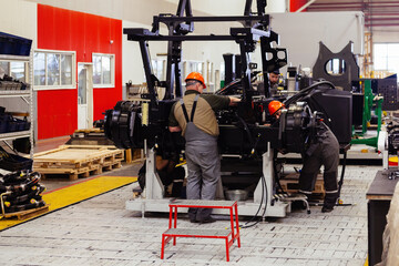 Industrial workers assembles agricultural machine in workshop