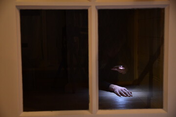 A scary picture of a reflection in a window of one hand in the light in a dark surrounding 