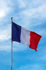 French flag on blue cloudy aky background.