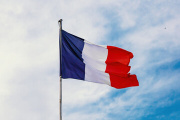 French flag on blue cloudy aky background.