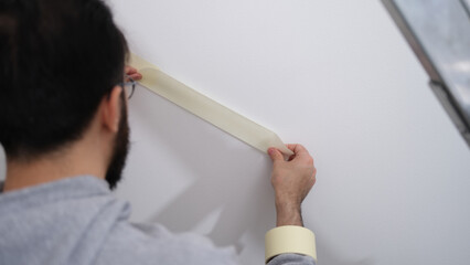 Home repair master using masking tape before painting