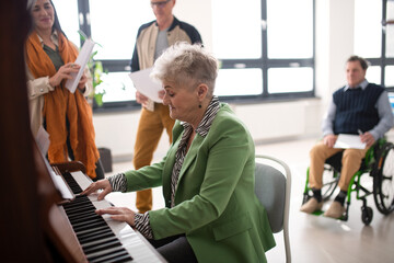 Senior woman playing at piano in choir rehearsal. © Halfpoint