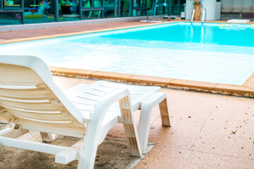 white beach chair is placed near the pool.