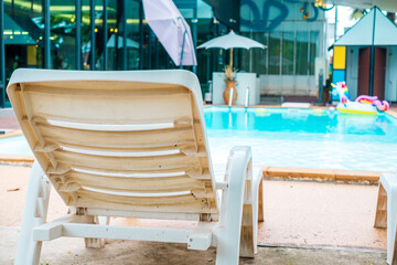 white beach chair is placed near the pool.