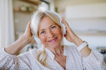 Senior woman with headphones listening to relaxation music at home
