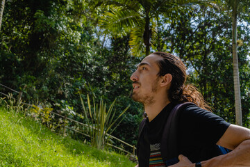 young latin man with long hair exploring nature, traveling in a tropical forest, low angle view. copy space