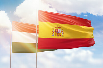 Sunny blue sky and flags of spain and hungary