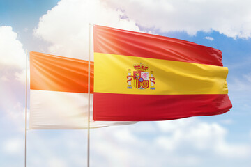 Sunny blue sky and flags of spain and indonesia