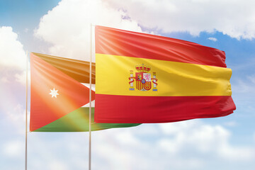Sunny blue sky and flags of spain and jordan