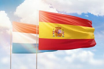Sunny blue sky and flags of spain and luxembourg