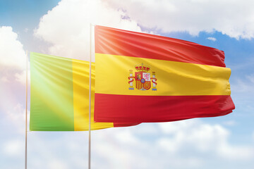 Sunny blue sky and flags of spain and mali