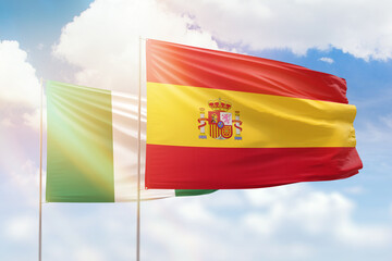 Sunny blue sky and flags of spain and nigeria