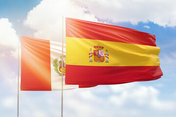 Sunny blue sky and flags of spain and peru