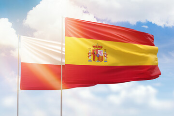 Sunny blue sky and flags of spain and poland