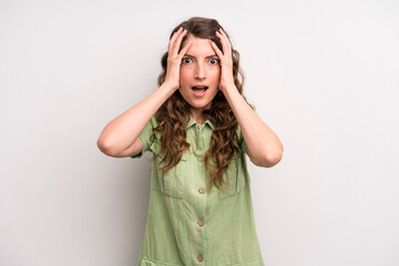 young adult pretty woman feeling horrified and shocked, raising hands to head and panicking at a...