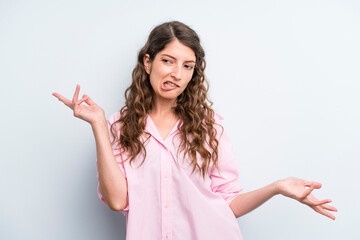 young adult pretty woman shrugging with a dumb, crazy, confused, puzzled expression, feeling...