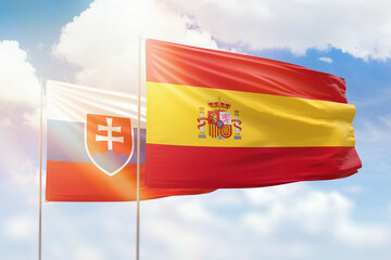 Sunny blue sky and flags of spain and slovakia