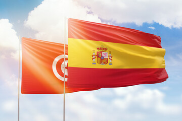 Sunny blue sky and flags of spain and tunisia