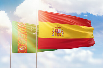 Sunny blue sky and flags of spain and turkmenistan