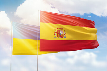 Sunny blue sky and flags of spain and ukraine