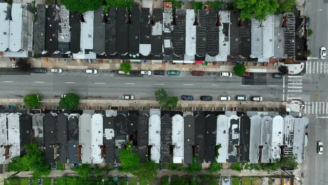 Top down aerial of rooftop view of rowhomes in USA city. Urban setting with street and sidewalk in summer.