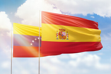 Sunny blue sky and flags of spain and venezuela