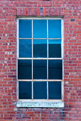 Close up of old window with white grilles and stone sill on old brick building, vintage aged building