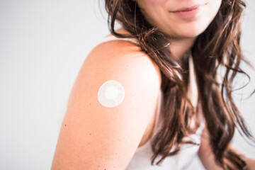 woman showing covid-19 or flu vaccination band-aid on her arm, protection from the pandemic and and...
