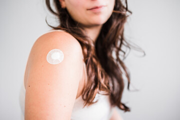 woman showing covid-19 or flu vaccination band-aid on her arm, protection from the pandemic and and...