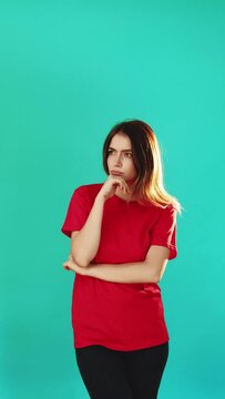 Clueless woman portrait. Whatever gesture. Vertical portrait of doubtful puzzled lady in red t-shirt shrugging isolated on turquoise blue copy space background. No idea. Fail sorry.