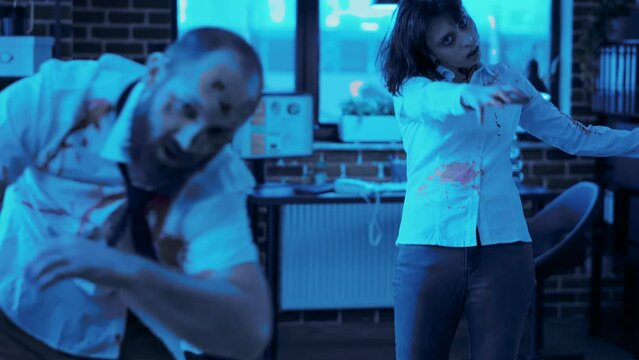 Brain-eating scary office zombies coming towards camera at night. Dead walking mindless corpses with deep and bloody wounds and scars while wandering in company workspace looking for survivors