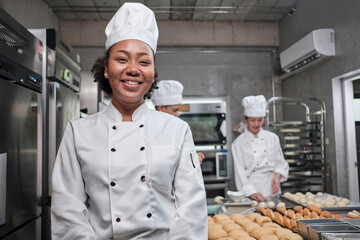 Portrait of young African American female chef in white cooking uniform looking at camera, cheerful...