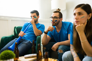 Worried sports fans watching the soccer championship together on tv