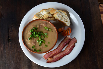 bean broth with herbs bread and bacon in a porcelain bowl, typical brazilian food, bean soup