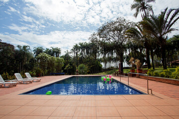 pool with white chairs and natural garden in the background