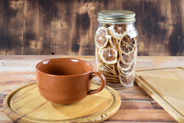 empty porcelain cup on wooden table, jar with dehydrated lemon in the background