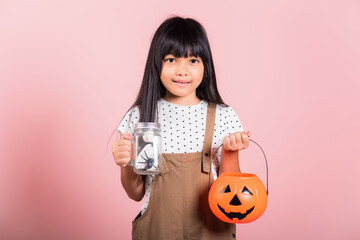 Asian little kid 10 years old holding Jack O pumpkin basket to collect candy trick at studio shot...