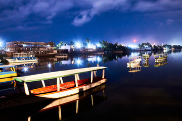 boats at night in lake with reflections on the water and dark sky in coyuca lagoon, pie de la...