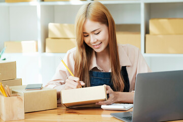 Online small business owner writing address on parcel box.