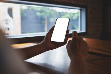 Mockup image of a woman holding and using mobile phone with blank white screen
