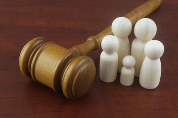 Family law concept. Judge gavel with many wooden figures of family members close-up.	